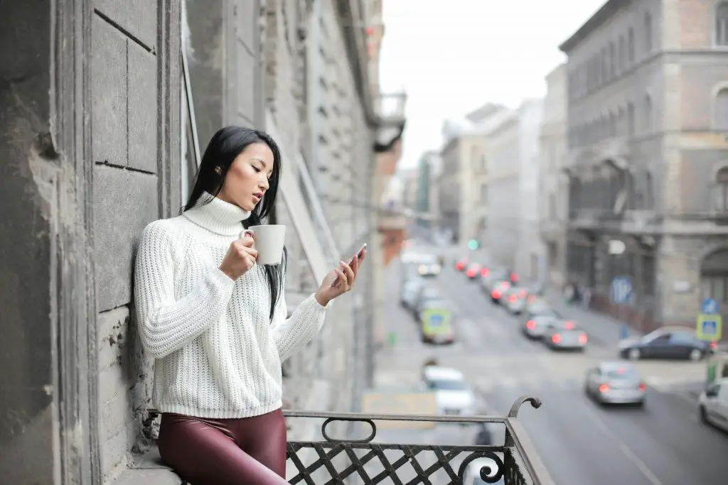 Woman in white sweater holding a white ceramic cup. Photo by Andrea Piacquadio.